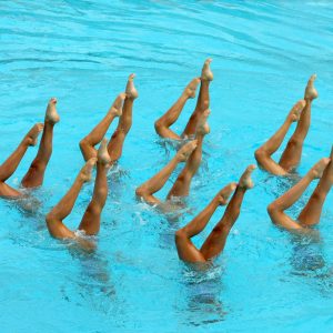 Synchronized Swimmers legs point up out of the water in action